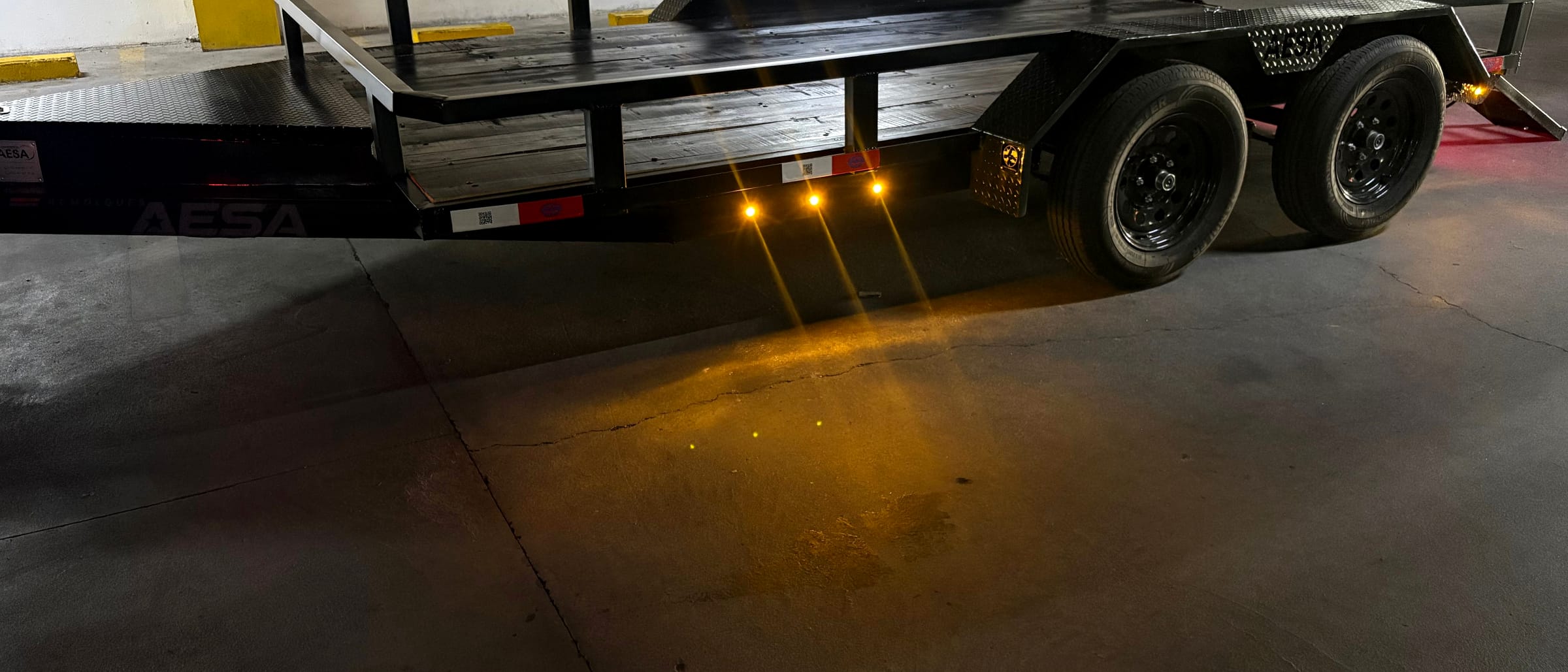 Remolque AESA con barandal y luces ámbar encendidas en un estacionamiento techado