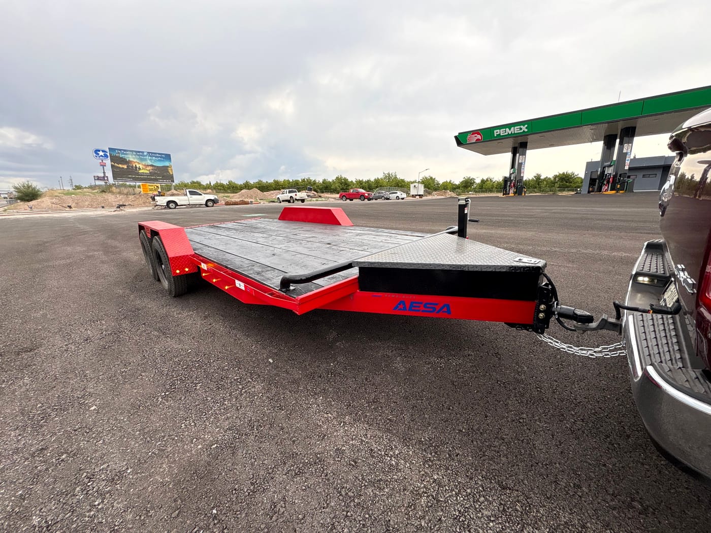 Car hauler rojo enganchado a una pickup, vista de tres cuartos