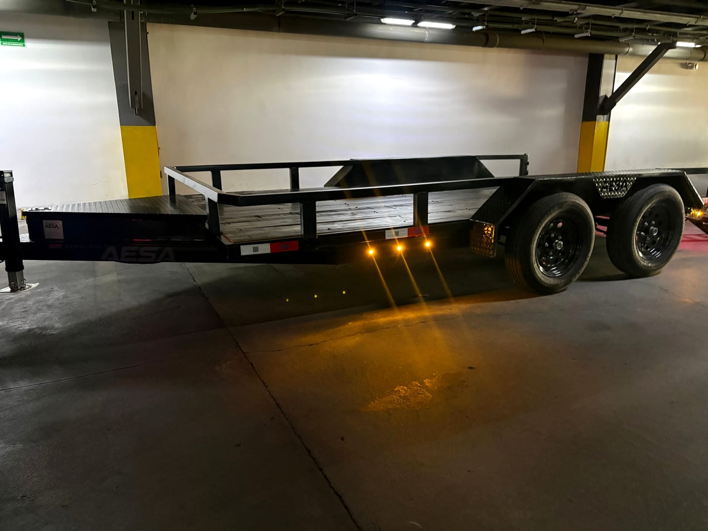 Remolque de plataforma negro con luces ámbar laterales encendidas